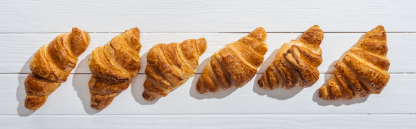panoramic shot of golden fresh and tasty croissants on white  - Photo, Image