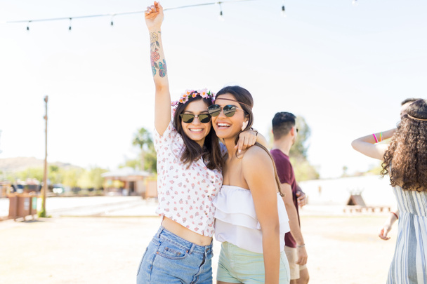 Portrait of gorgeous women wearing sunglasses while standing around at music festival - Photo, Image