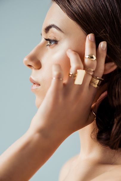 profile of young woman with golden rings isolated on grey - Photo, Image