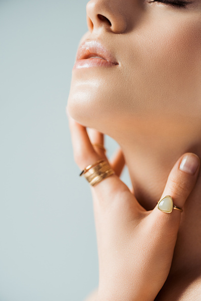 cropped view of young woman in golden rings touching neck isolated on grey - Foto, afbeelding
