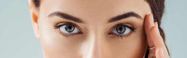 cropped view of young woman with golden eye shadow looking at camera isolated on grey - Photo, Image