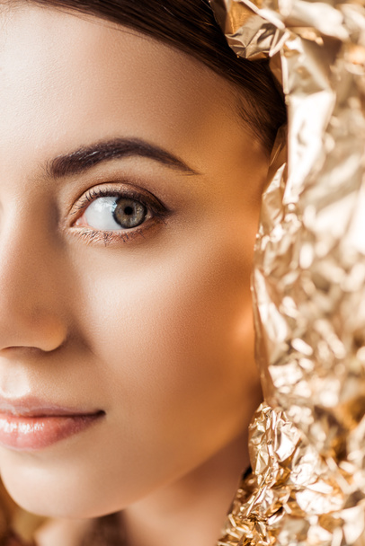 cropped view of young attractive woman with shiny makeup near golden foil  - Foto, imagen