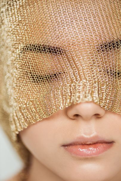 close up of young woman with closed eyes, shiny lips and golden cloth on face  - Foto, immagini