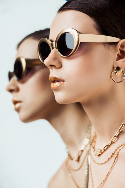 mladá nahá žena ve slunečních brýlích, zlatá náušnice a náhrdelníky u zrcadla s odrazem - Fotografie, Obrázek