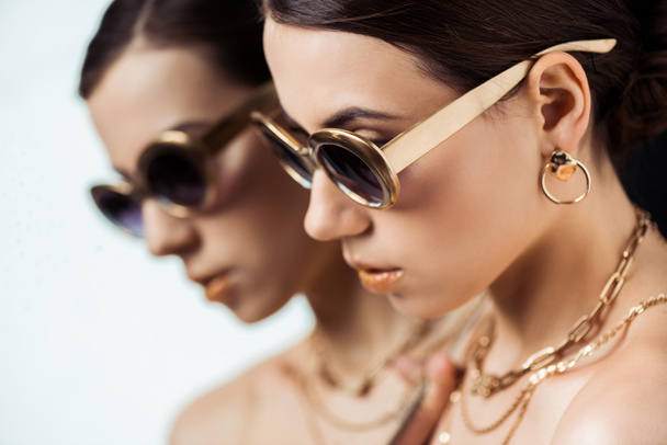 young naked woman in sunglasses, golden jewelry near mirror with reflection - Photo, Image