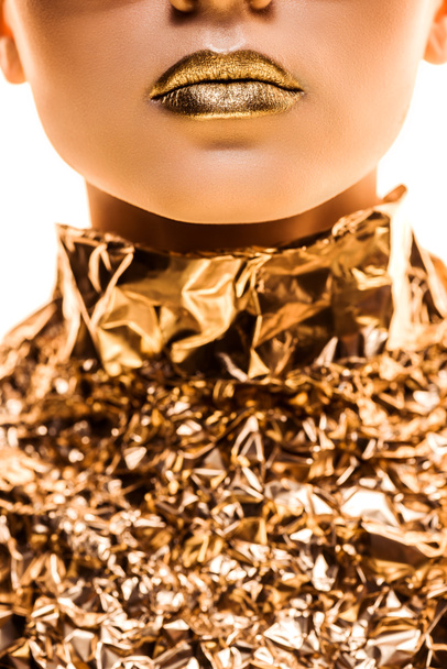 Teilansicht einer jungen Frau mit goldenen Lippen in goldener Folie isoliert auf weiß - Foto, Bild