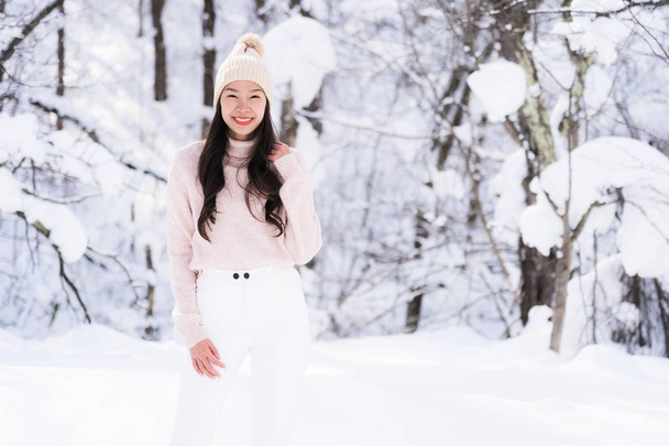 若い美しいアジアの女性の肖像画は楽しい旅を笑顔し、北海道札幌で雪で冬の季節を楽しむ - 写真・画像