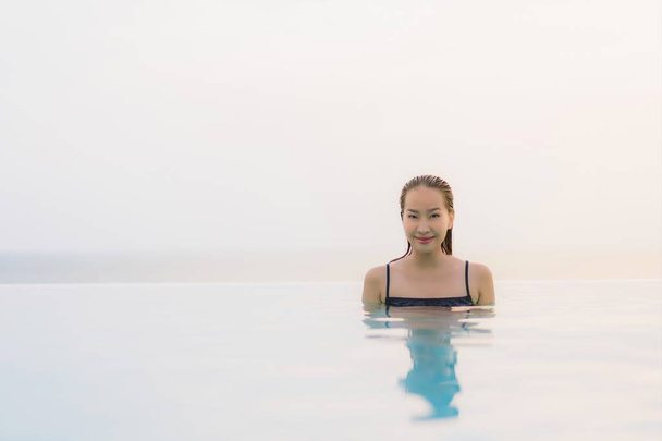 Portrait beautiful young asian woman happy smile relax around swimming pool in hotel resort for leisure travel and vacation at sunset - Fotó, kép