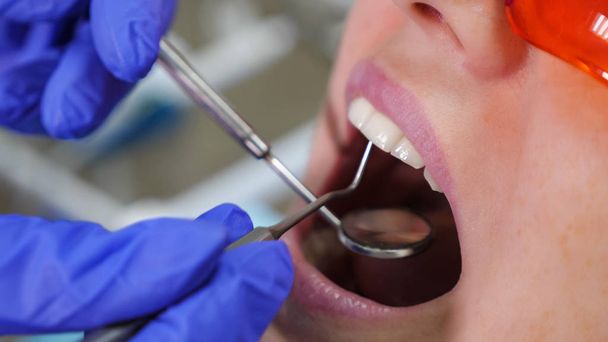 Dentist treating teeth to woman patient in clinic. - Zdjęcie, obraz