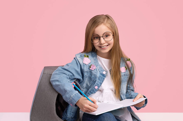 Clever girl smiling and doing homework - Фото, изображение
