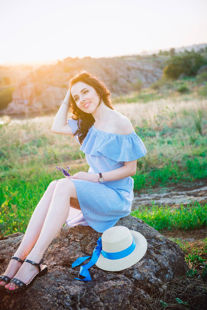 Portrait of young woman in blue romantic dress and straw hat in sun light enjoying summer sunset on nature. Calm and harmony. Summer vacation,fun, positive mood. Back sun light, sun beams. Copy space. - Foto, immagini