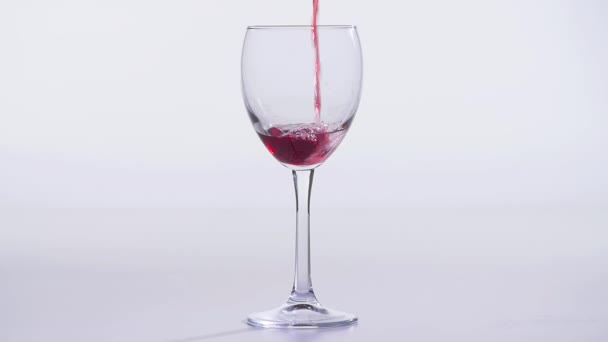 Concept van eten en drinken. Rode of roze wijn gegoten in een glas op een witte achtergrond. - Video