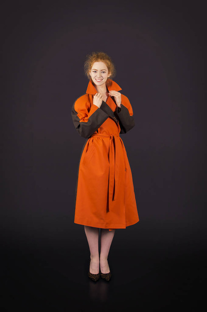 Beautiful, red-haired girl in an orange cloak posing. - Valokuva, kuva