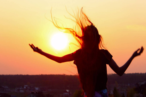 Sylwetka młodej kobiety trzymając ręce w górę i patrząc na zachód słońca. Ludzie, Podróże, hobby, koncepcja szczęścia. - Zdjęcie, obraz