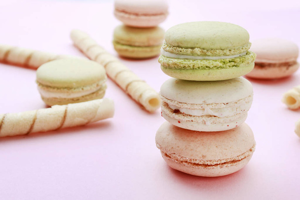 French macaroons and crispy wafer rolls on pink background.  - Photo, image