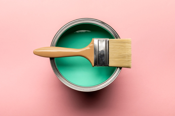 top view of tin of green paint and brush on pink surface - Foto, Imagen
