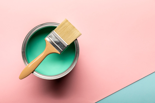 top view of tin of green paint and brush on pink surface - Fotoğraf, Görsel