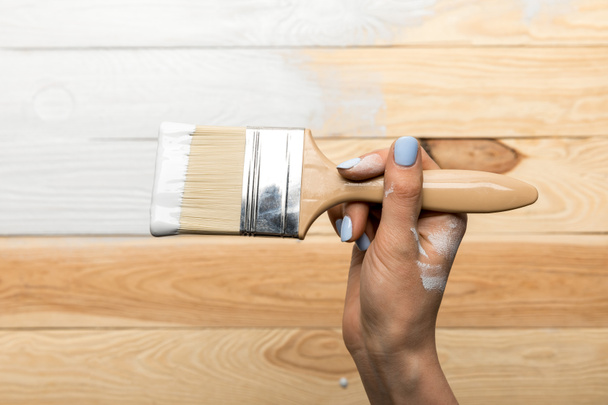 cropped view of woman painting wooden surface in white - Foto, Bild