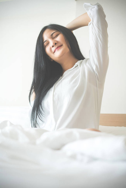 Beautiful young woman wake up and stretch oneself in the morning - Photo, Image