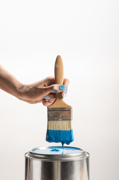 partial view of woman holding brush with blue paint on white - Foto, afbeelding