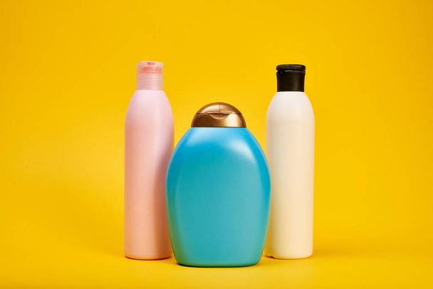 Studio shot of bottles with hair shampoo and gel showers on yellow background - Photo, image