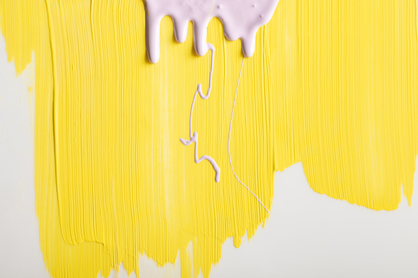 painted yellow background with flowing purple paint and copy space - Foto, Bild