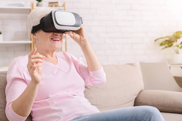 Senior woman watching video via vr glasses - Foto, Bild
