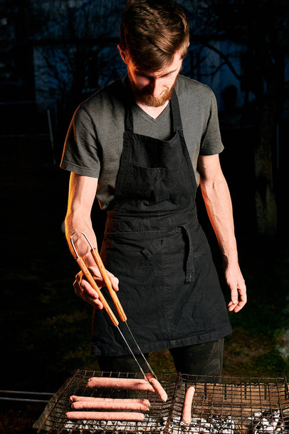 Man cooking sausages on grill  - Fotoğraf, Görsel
