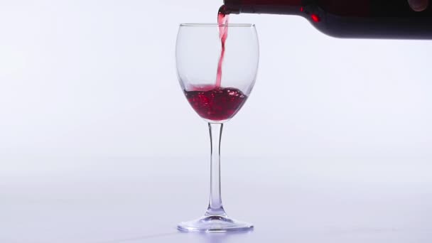 Η έννοια του φαγητού και των ποτών. Κόκκινο ή ροζ κρασί χύνεται σε ένα γυαλί σε λευκό φόντο. - Πλάνα, βίντεο