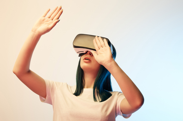 brunetta giovane donna indossando cuffie realtà virtuale e gesticolando su beige e blu
  - Foto, immagini