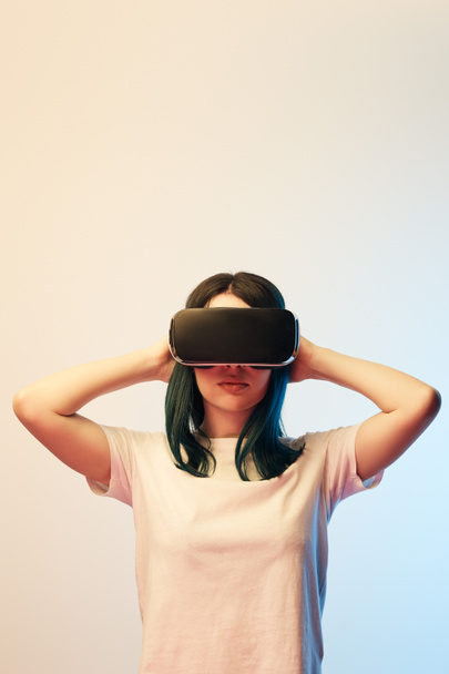 brunette young woman wearing virtual reality headset on beige and blue  - Fotó, kép