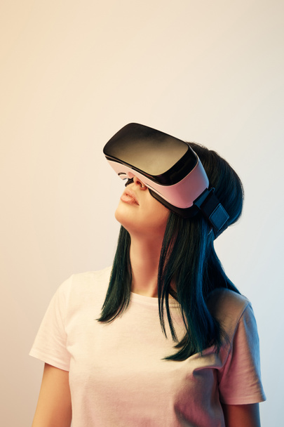 brunette vrouw dragen Virtual Reality headset op beige en blauw - Foto, afbeelding