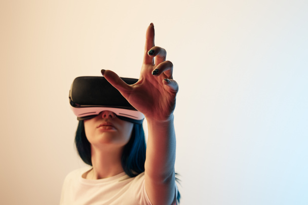 Selektiver Fokus des brünetten Mädchens mit Virtual-Reality-Headset und Gesten in Beige und Blau - Foto, Bild