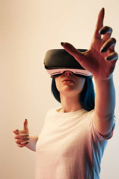 selektiver Fokus eines brünetten Mädchens, das Virtual-Reality-Headset trägt und auf beige gestikuliert  - Foto, Bild