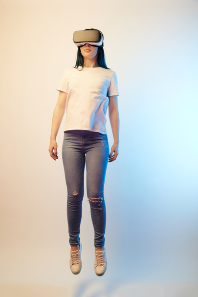 young woman in virtual reality headset levitating on beige and blue  - Photo, Image