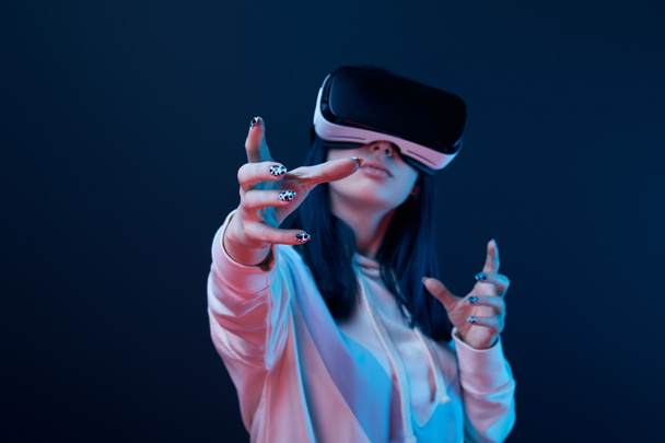 selective focus of girl wearing virtual reality headset and gesturing on blue  - Photo, Image