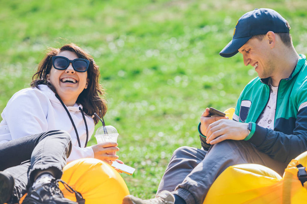 casal que põe no colchão inflável no parque da cidade no dia ensolarado. falar e conversar
 - Foto, Imagem