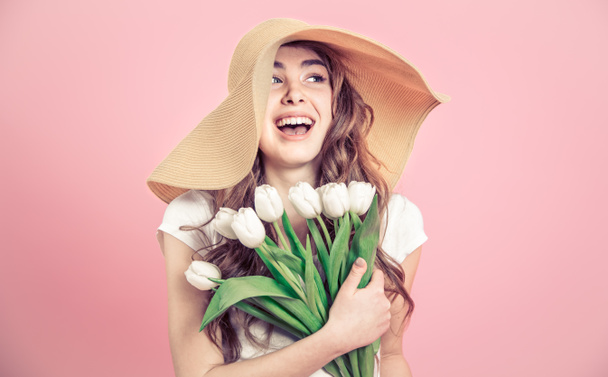 girl in a hat and tulips on a colored background - Foto, imagen