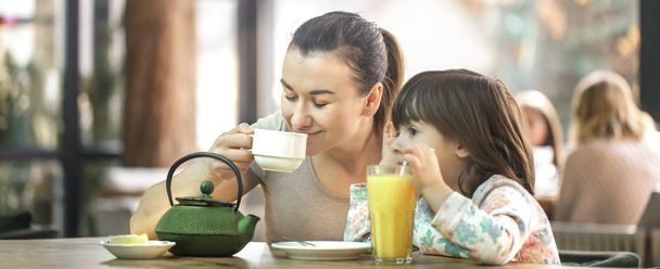 Mom and little daughter are drinking tea in a cafe - Foto, Bild