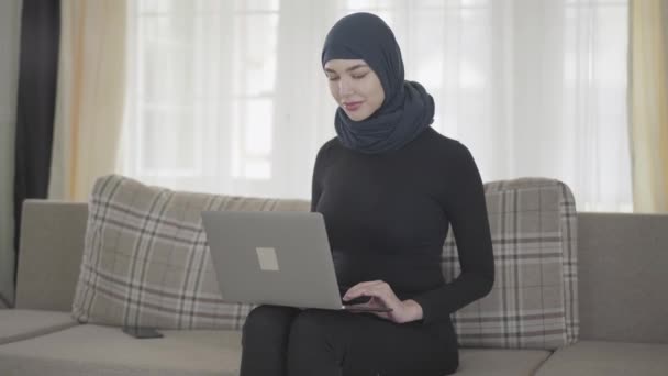 Young muslim woman was working or chatting by laptop and after somebody called her by the smartphone - Séquence, vidéo