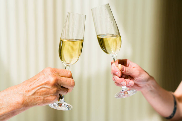 рука пожилой женщины и молодой женщины тост с бокалами ч
 - Фото, изображение