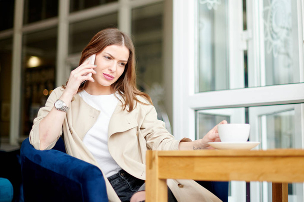 Mujer joven en la cafetería con teléfono y café
 - Foto, Imagen