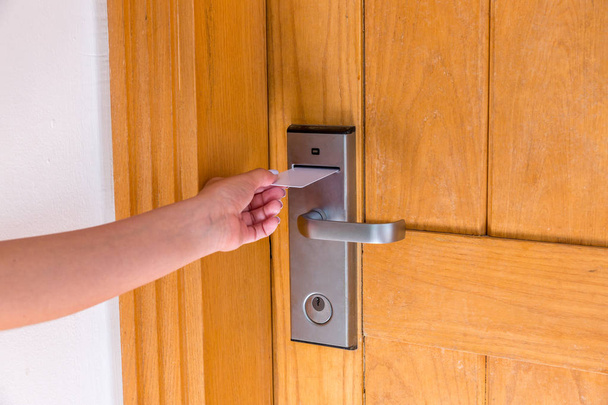 Θηλυκό χέρι βάζοντας και κρατώντας μαγνητική κάρτα κλειδί διακόπτη στο άνοιγμα της πόρτας του δωματίου του ξενοδοχείου - Φωτογραφία, εικόνα