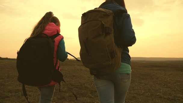 Mom and daughter travel with a backpack against the sky. tourists mother and child go to sunset in the mountains. happy family on vacation travels. sports tourism concept. - Photo, Image
