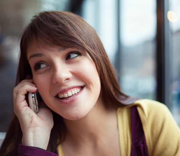 Beautiful young girl on the phone in a cafe - Фото, зображення
