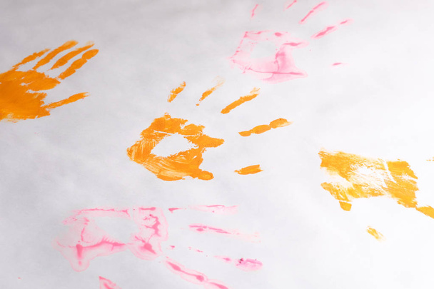 a little imprint of children's hands on a white paper background, multi-colored hands - Fotó, kép