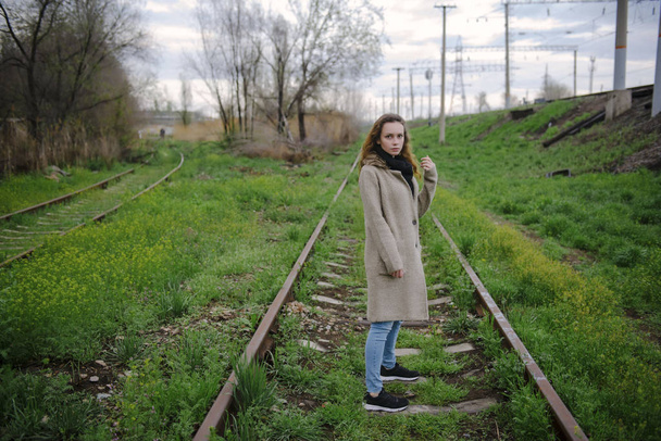 A young woman walks on railroad tracks. - Φωτογραφία, εικόνα