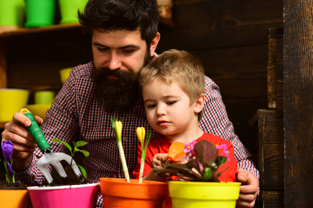 Family day. Greenhouse. Father and son. Fathers day. Flower care watering. Soil fertilizers. happy gardeners with spring flowers. bearded man and little boy child love nature. Eco living - Fotoğraf, Görsel