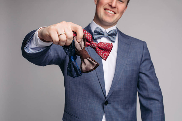 Smiling man insmart suit keeping bow ties in hand - Photo, Image