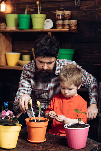 Flower care watering. Soil fertilizers. happy gardeners with spring flowers. Father and son. Fathers day. Family day. Greenhouse. bearded man and little boy child love nature. Work for you - Zdjęcie, obraz